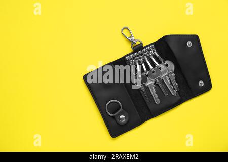 Open leather holder with keys on yellow background, top view. Space for text Stock Photo