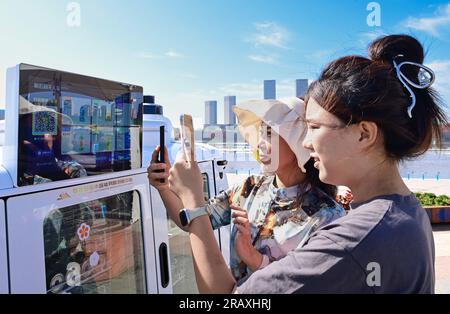 ORDOS, CHINA - JULY 6, 2023 - Tourists shop at a self-driving vending vehicle on a street in Ordos, Inner Mongolia, China, July 6, 2023. In recent yea Stock Photo