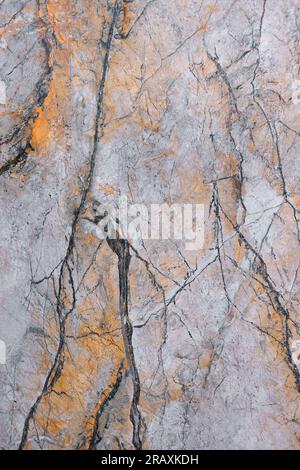 The marble surface with a pinkish-yellow tint is covered with cracks and spots. Stock Photo