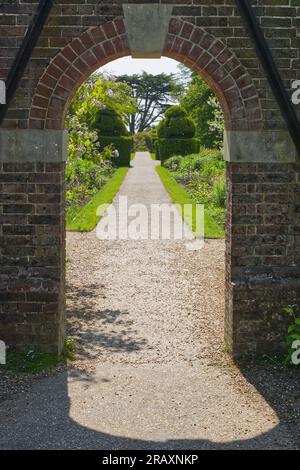 Arched doorway in old brickwall leading to an English country garden. Stock Photo