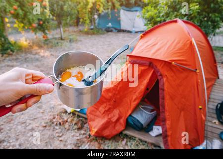 freeze-dried camping food - rice with dried fruits in a pot on the background of a tent in a camping Stock Photo