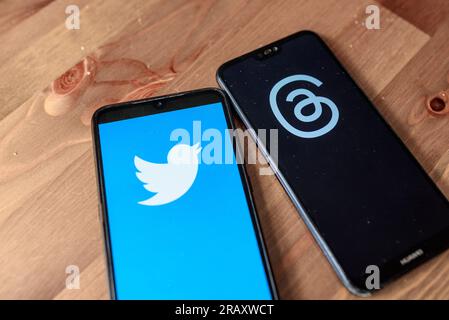In this photo illustration the app Threads from Meta logo and the Twitter logo are seen on the display of two mobile phones on a table. Threads is the Stock Photo