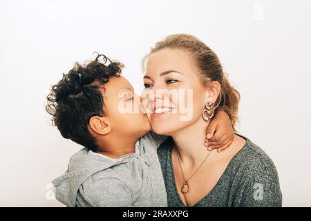 Studio shot of adorable toddler boy giving a kiss to his mother Stock Photo