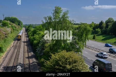 Train in West Midlands Trains livery travelling along track running parallel with the M40 motorway, Warwickshire, England. Stock Photo