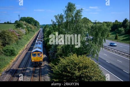 Freight train travelling along track running parallel with the M40 motorway, Warwickshire, England. Stock Photo