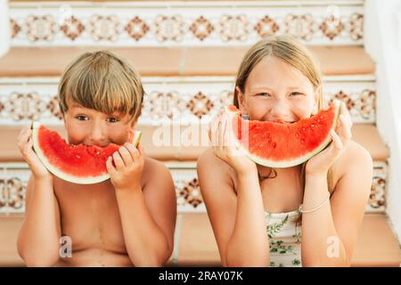 Outdoor summer portrait of two funny kids eating watermelon Stock Photo