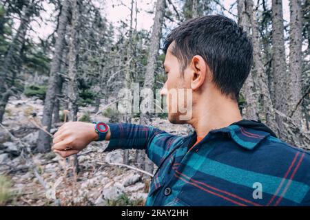 Hiker man with wristwatch in the woods on a trail Stock Photo