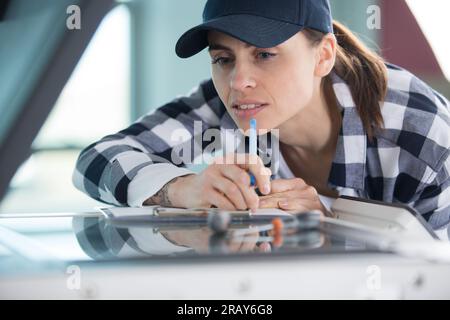 young woman adjusts settings on plotter in printing office Stock Photo