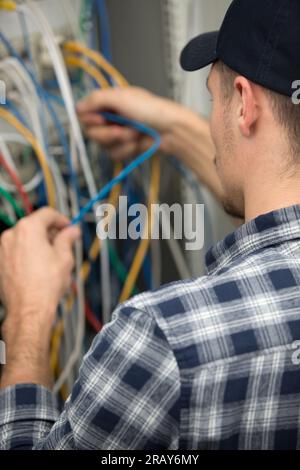 side view portrait of young man connecting wires in server Stock Photo