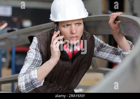 female worker speaking by phone while supervising production at plant Stock Photo