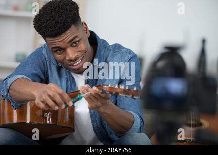 hipster filming tutorial on how to tune a guitar Stock Photo