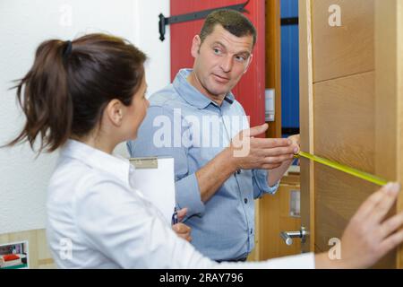 couple measuring furniture with tape measure against white background Stock Photo