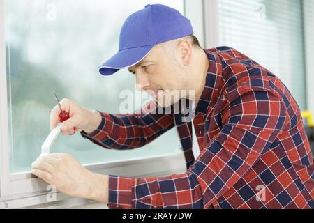 worker fasten the handle to a plastic window Stock Photo