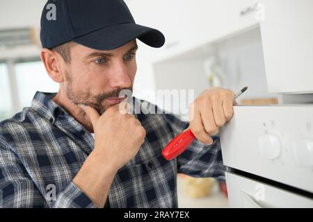 technician is fixing oven in kitchen Stock Photo