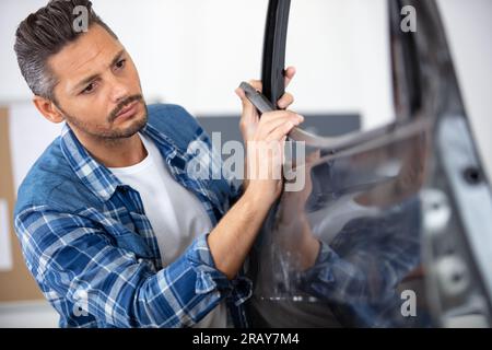 mechanic fitting a door rubber Stock Photo