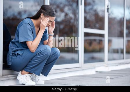 Anxiety, doctor or a woman with a headache from healthcare, surgery mistake or death at a hospital. Sad, depressed and a tired female nurse with a Stock Photo
