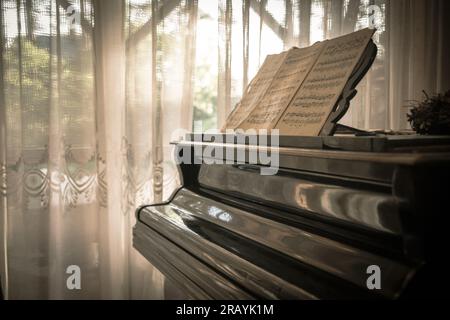 Artistic short depth of field photo of closed piano keyboard with the reflection of soft. warm yellow daylight toned bokeh lights in the background. Stock Photo