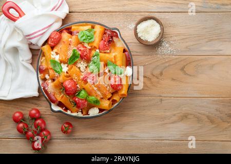 Pasta Tortiglioni with tomato sauce, baked cherry tomatoes, mozzarella and parmesan cheese, basil on old rustic table background. Traditional Italian Stock Photo