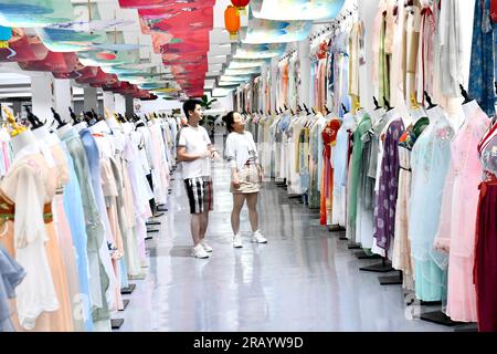 Caoxian, China's Shandong Province. 6th July, 2023. Customers select traditional Chinese Hanfu clothing at a Hanfu base in Caoxian County, east China's Shandong Province, July 6, 2023. Caoxian County has developed a complete Hanfu industrial chain in recent years. At present, there are more than 2,100 Hanfu-related enterprises in the county. The sales of Hanfu in Caoxian reached nearly 4 billion yuan (about 552 million U.S. dollars) in the first half of this year. Credit: Guo Xulei/Xinhua/Alamy Live News Stock Photo