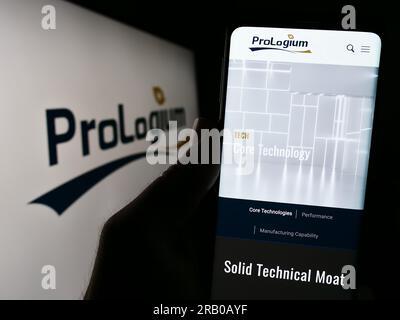 Person holding cellphone with webpage of Taiwanese company ProLogium Technology Co. Ltd. on screen with logo. Focus on center of phone display. Stock Photo