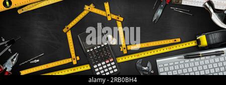 Folding wooden ruler in the shape of a house on a workbench with work tools, calculator, Euro coins, computer keyboard and copy space. Stock Photo
