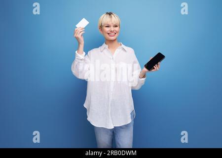 young positive caucasian office worker woman with a bob haircut and dressed in a white blouse uses online transfers using a smartphone and a map. e Stock Photo