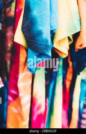 Array of colorful unisex tie-dye shirts. Selective focus. Closeup. Stock Photo