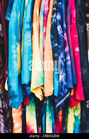 Array of colorful unisex tie-dye shirts. Selective focus. Closeup. Stock Photo
