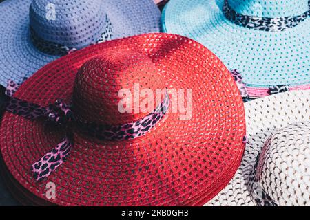Colorful women's UV protection wide brim and breathable beach straw hat with leopard bowknot for protection against the sun's rays. Selective focus. Stock Photo
