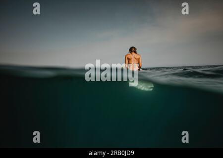 Surfer woman sitting on surfboard in water Stock Photo