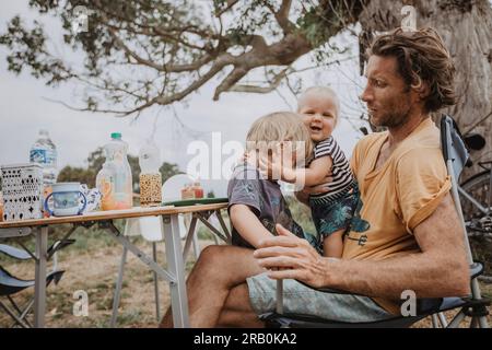 Father sitting with his children at camping table Stock Photo