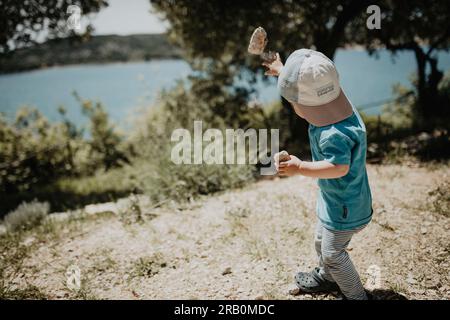 Boy throwing a stone by the sea, island Krk, Croatia Stock Photo