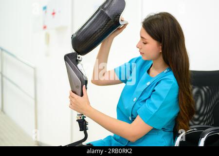 Female technician holding prosthetic limb checking in medical clinic Stock Photo