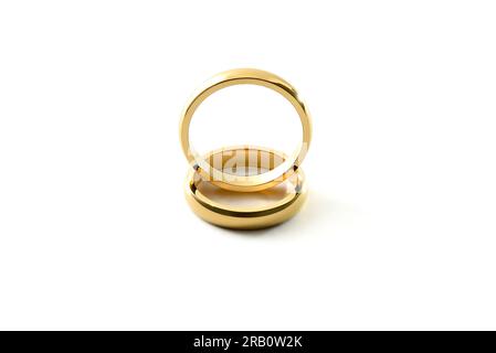 Detail of engagement gold ring standing on each other on white textured base. Elevated front view. Stock Photo