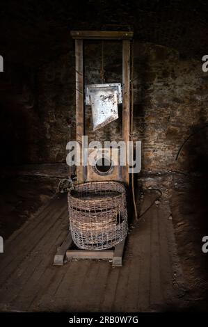 working historic Guillotine made from wood and blade located in a dark cellar Stock Photo