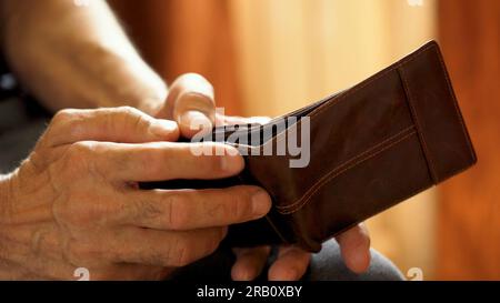 An elderly man's hands, covered with knotted veins, search for coins in his wallet Stock Photo