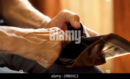 An elderly man's hands, covered with knotted veins, search for coins in his wallet Stock Photo