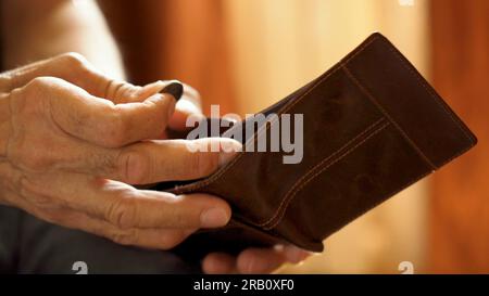 An elderly man's hands, covered with knotted veins, search for coins in his wallet Stock Photo