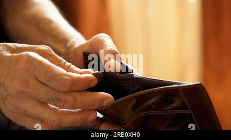 An elderly man's hands, covered with knotted veins, search for coins in his wallet Stock Photo