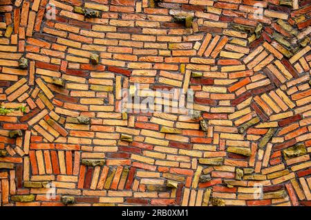 Wall with haphazardly stacked bricks in various shades of yellow, orange and red Stock Photo
