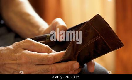 An elderly man's hands, covered with knotted veins, search for coins in his wallet Stock Photo
