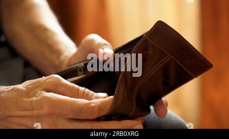 An elderly man's hands, covered with knotted veins, search for coins in his wallet Stock Photo