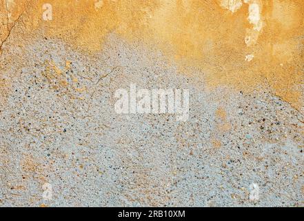 Colorful background of old plaster with remnants of ocher color paint. Stock Photo