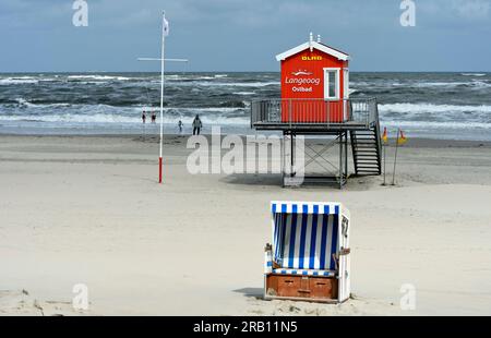 Empty beach chair and unoccupied watchtower of the German Life Saving Society, DLRG, on a cool and windy day in the early season on the beach of Langeoog, East Frisian Islands, Lower Saxony, Germany. Stock Photo