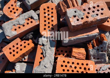 A pile of old red bricks with the remains of dried mortar. Building material red brick with holes. Solid clay bricks used for construction. Concept of Stock Photo