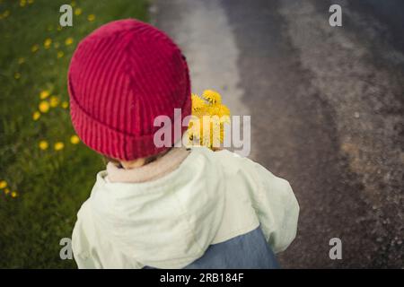Boy with bouquet of flowers walks along a dirt road Stock Photo