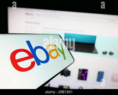 Smartphone with logo of American e-commerce company eBay Inc. on screen in front of business website. Focus on left of phone display. Stock Photo