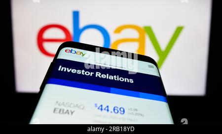 Mobile phone with webpage of US e-commerce company eBay Inc. on screen in front of business logo. Focus on top-left of phone display. Stock Photo