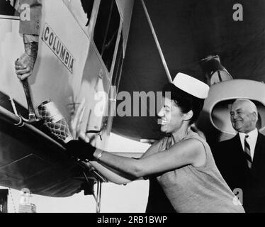 Akron, Ohio:  August 27, 1963 Miss America, Jacquelyn Mayer, gets a  helping hand hammer from the pilot as she christens the gondola of Goodyear's new blimp, Columbia. Goodyear Chairman E. J. Thomas watches the ceremony. Stock Photo