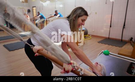 Happy Pilates coach instructing a senior woman to strengthen body with equipment Stock Photo